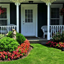 The front porch of a house, with lawn and flower garden.